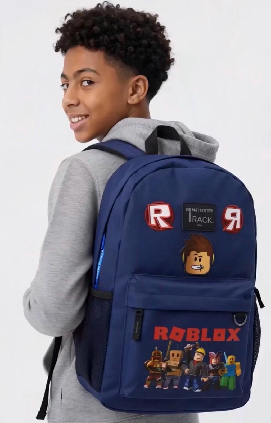 A boy wearing a gray hoodie and black pants is shown from the back, wearing a navy blue gaming backpack 